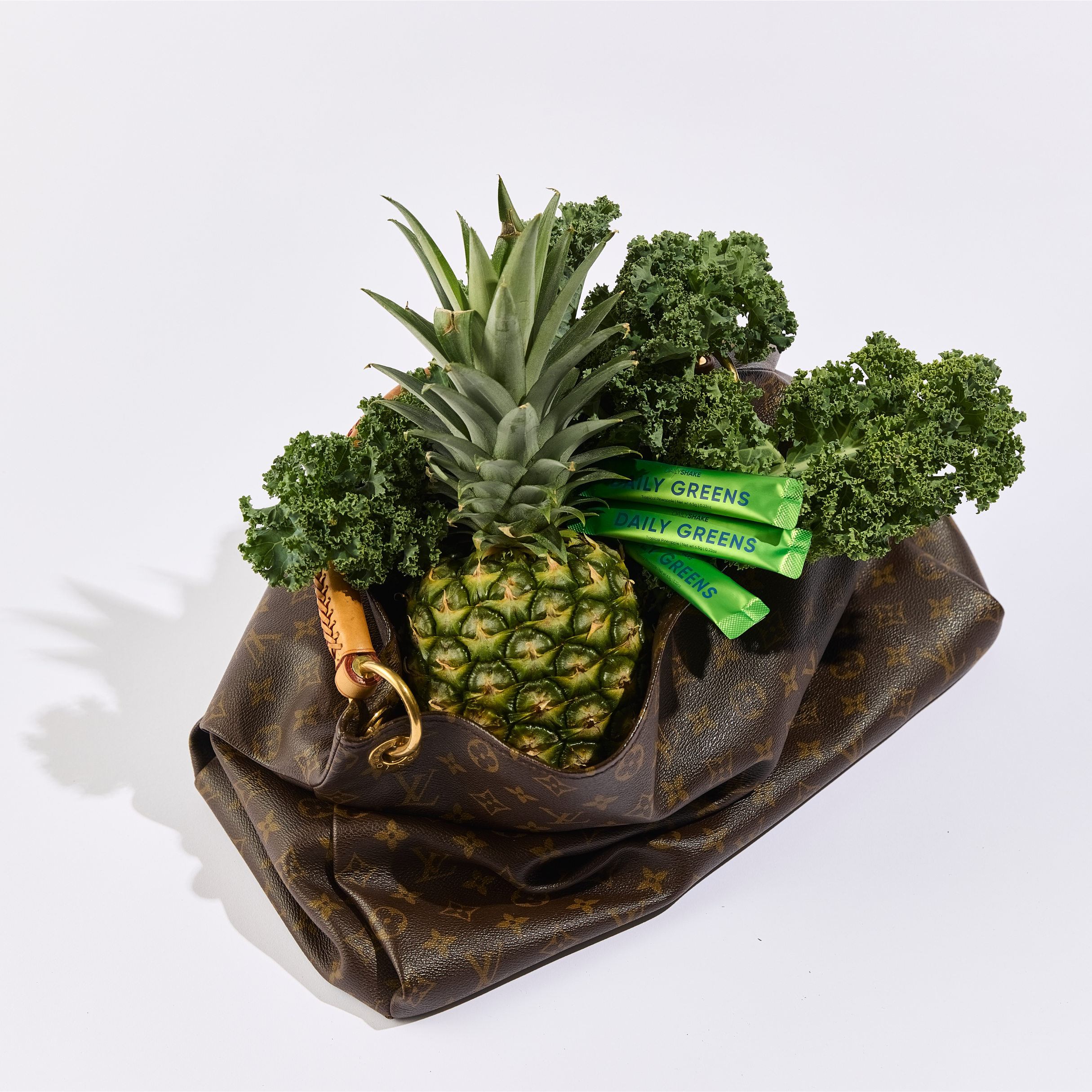 Pineapple and kale on a brown fabric bag with a white background