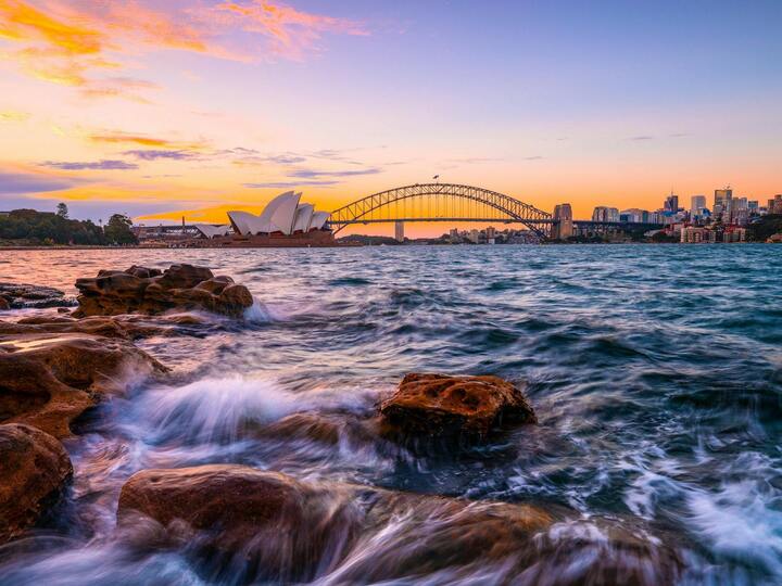Sunset over Sydney Harbour with the Sydney Opera House and Harbour Bridge in the background.