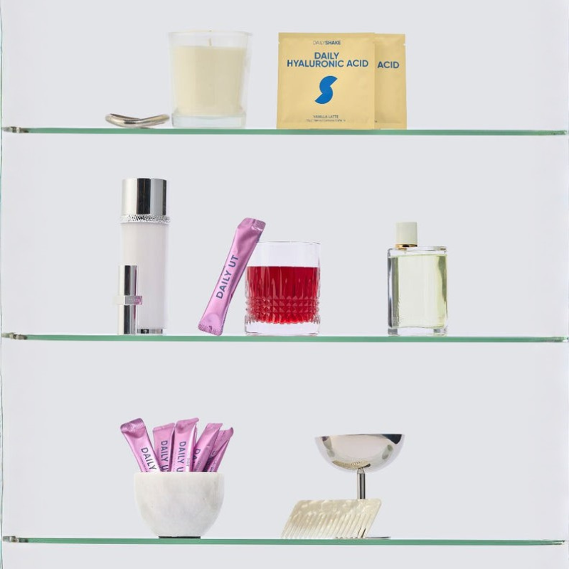 Glass shelves with skincare products including bottles, packets, and a candle.